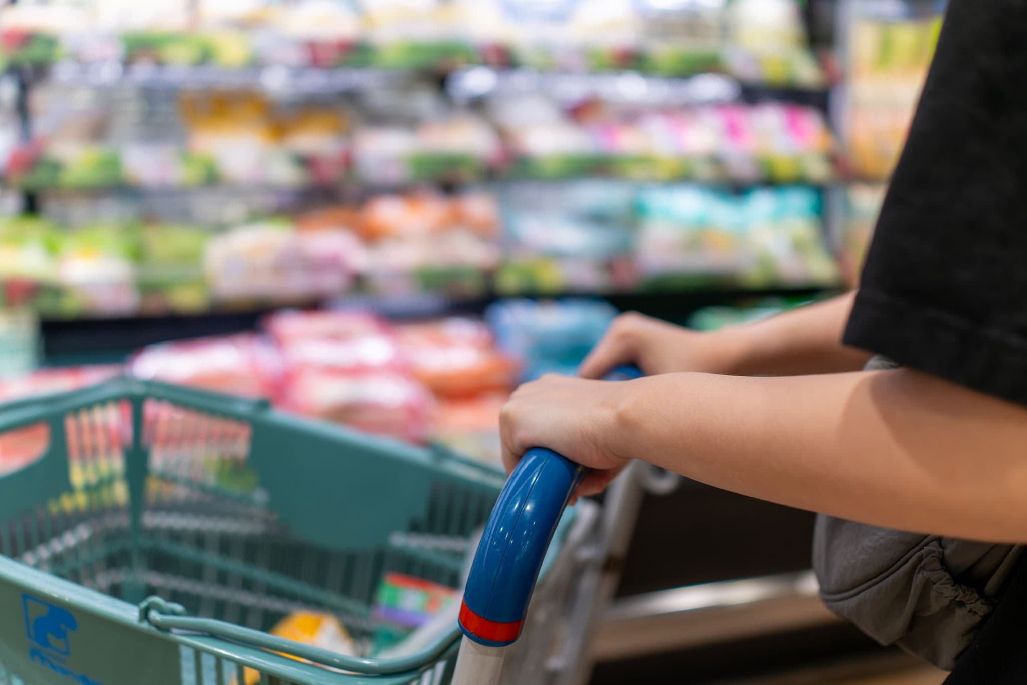 Shopper pushing a trolley through a supermarket aisle